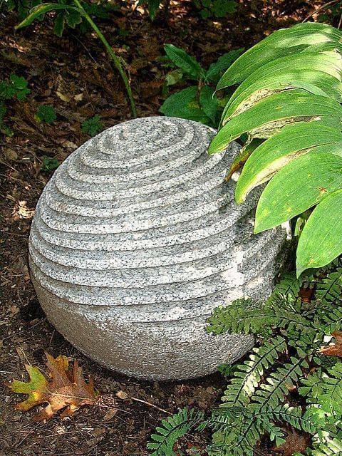 Image 11: ribbed spiral concrete garden sphere among ferns