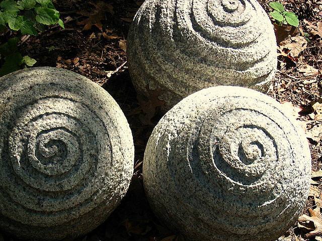 Three textured spiral stone spheres in shade